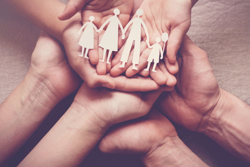 Grupo de manos que sostienen una familia hecha con papel