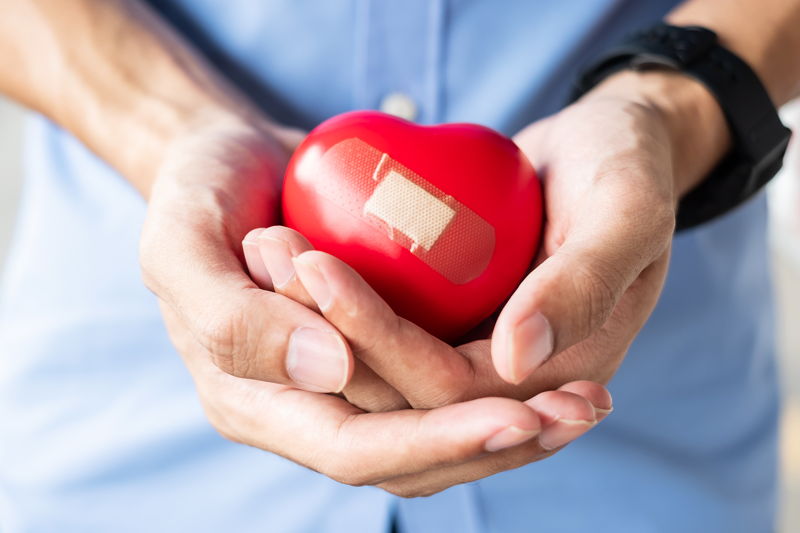 Manos sosteniendo un corazón con esparadrapo