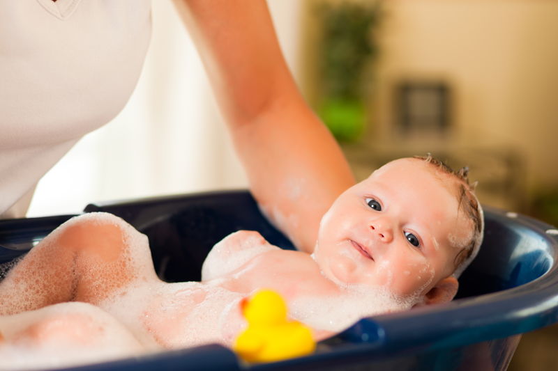 Madre bañando a su hijo en una bañera llena de jabón