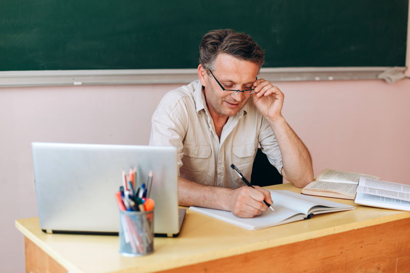 Profesor con gafas tomando notas en su registro de clase
