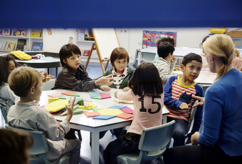 Maestra haciendo una comunicación a niños muy atentos en la clase