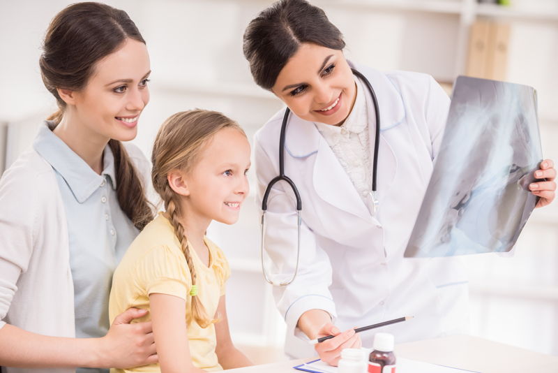 Médico enseñando una imagen de rayo X a una madre con su hija