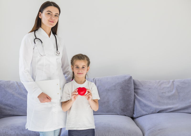 A physician with a little girl holding a red heart