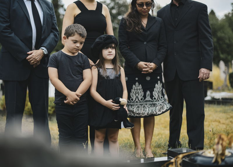 Niños asistiendo a un funeral con entierro