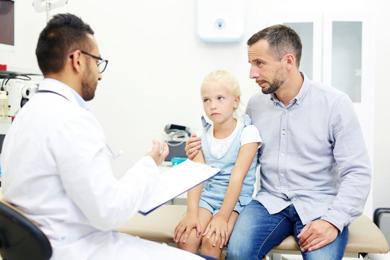 Padre con su hija hablando con un profesional de la salud