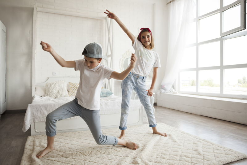 Niño y niña bailando encima de una alfombra blanca
