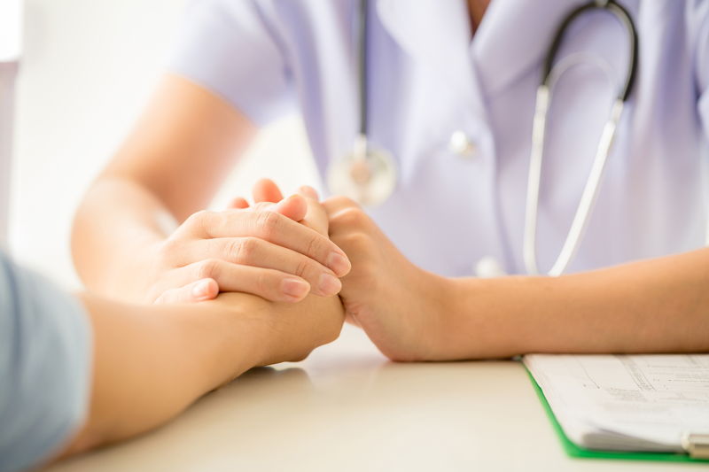 Mano de un profesional de atención médica sujetando la mano de un paciente