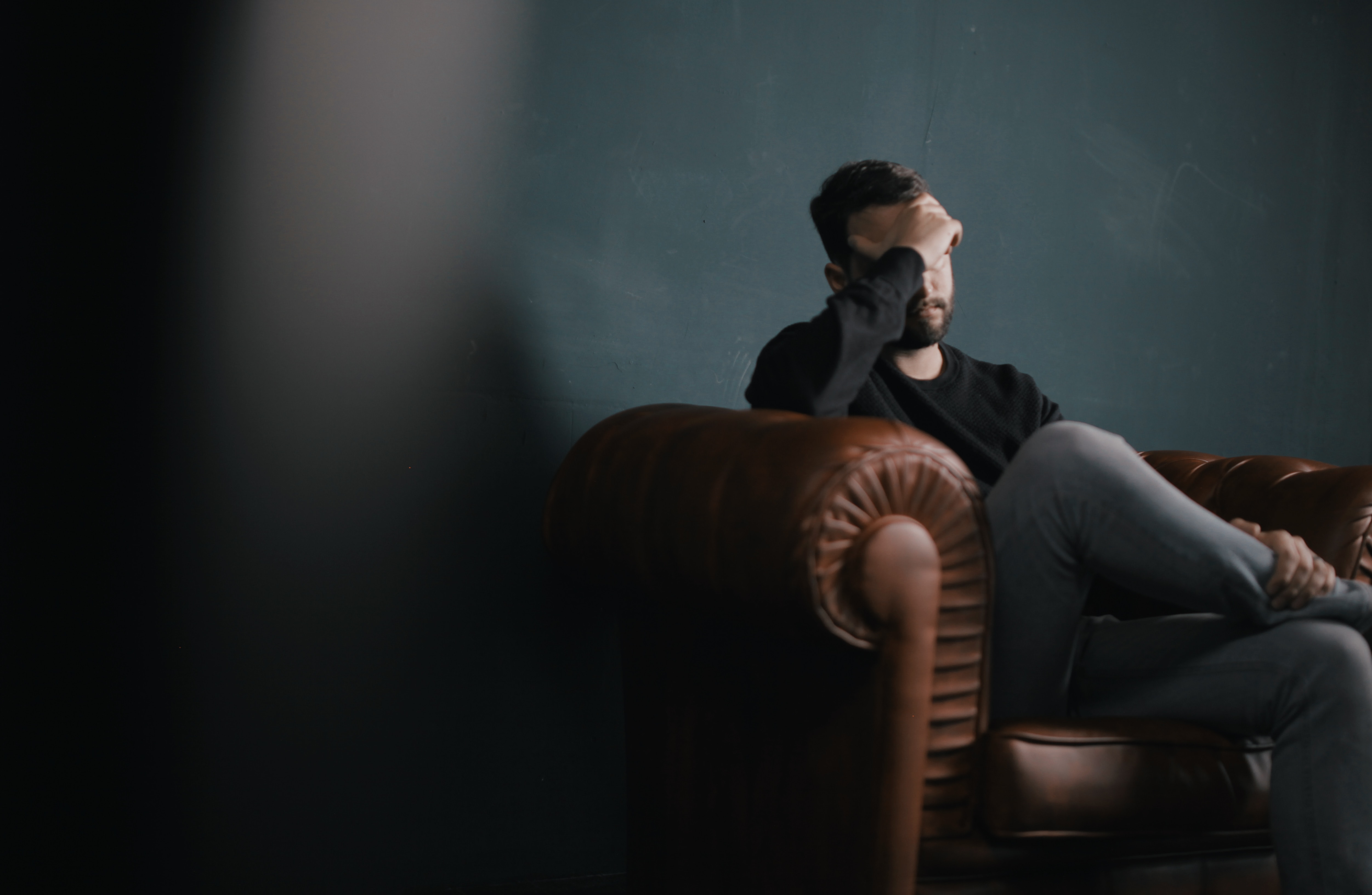 Man on a sofa worried hand on his face