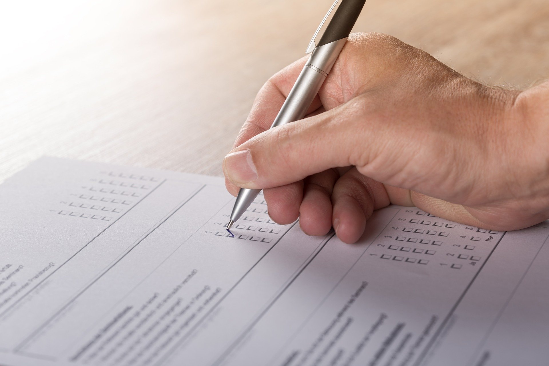 Hand of a man with a pen filling up a survey