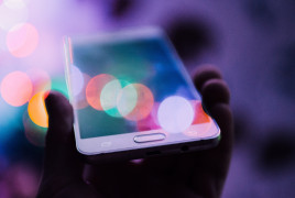 A smartphone, a hand of a person and colorful lights