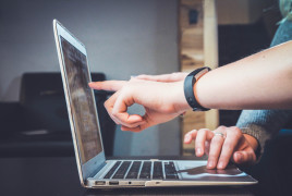 Person working on a laptop and pointing the screen