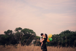 Mum and son kissing each other on a field and holding balloons