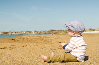 Kid with his clothes on sitting on a beach