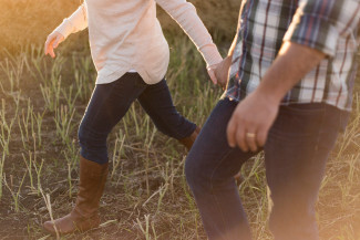 Man and women holding hands walking on the countryside