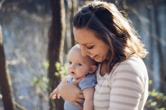 Webinar_Gilly Mom laughing holding her small kid in the sunny woods
