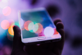 10 reasons to join Share4Rare A smartphone, a hand of a person and colorful lights