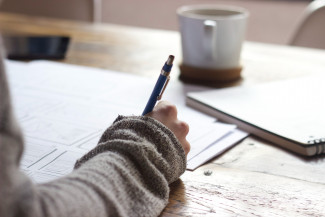 Rare Advocacy toolkit Person writing and with a cup of coffee on the desk