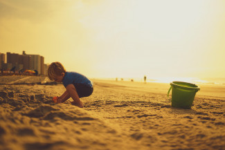 A child playing on the beach under the sun 