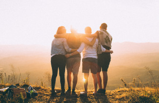 4 people staring at the sunset holding 