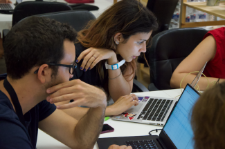 Two people programming on a laptop