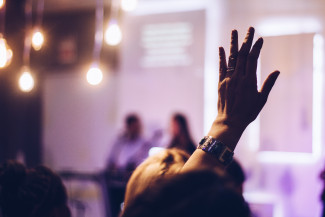 Hand raised by a woman during a meeting or seminar