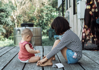 Baby with older girl playing on a porch