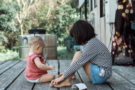 Baby with older girl playing on a porch