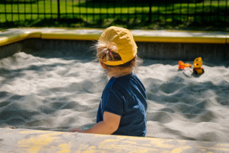 Kid playing in a sunny playground wearing a yellow cap