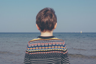 Boy with a sweater looking at the sea